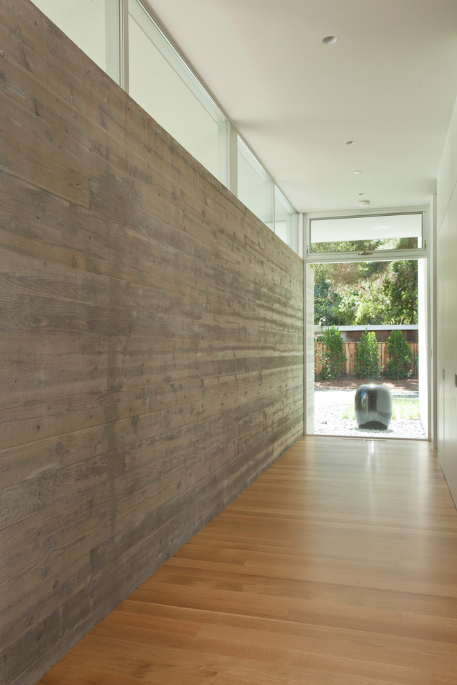 This is an example of a large modern hallway in San Francisco with light hardwood floors.