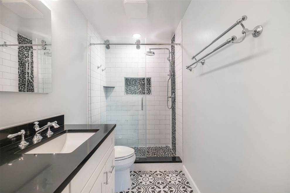 Design ideas for a mid-sized country master bathroom in DC Metro with shaker cabinets, white cabinets, an alcove shower, a two-piece toilet, white tile, subway tile, grey walls, porcelain floors, an undermount sink, engineered quartz benchtops, multi-coloured floor, a sliding shower screen, black benchtops, a niche, a double vanity and a built-in vanity.