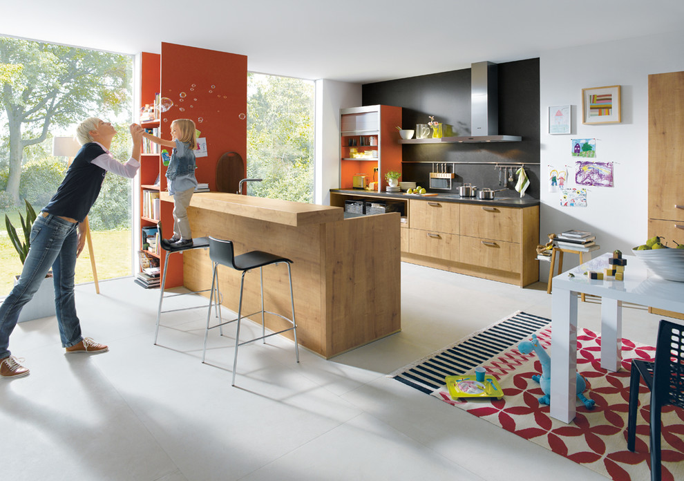 Photo of a medium sized modern galley kitchen/diner in Surrey with flat-panel cabinets, medium wood cabinets, granite worktops, stainless steel appliances and a breakfast bar.