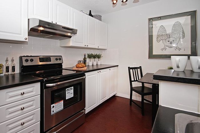 Inspiration for a small transitional cork floor kitchen remodel in Calgary with raised-panel cabinets, white cabinets, white backsplash, ceramic backsplash, stainless steel appliances and a drop-in sink