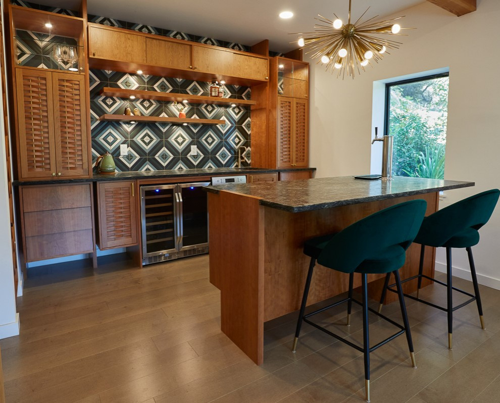 Example of a mid-sized 1950s galley light wood floor and beige floor home bar design with an undermount sink, granite countertops, green backsplash, ceramic backsplash and black countertops