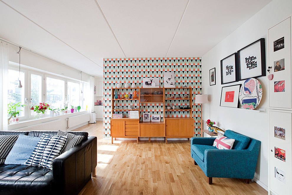 This is an example of a mid-sized midcentury open concept living room in Stockholm with white walls, light hardwood floors, no fireplace and no tv.