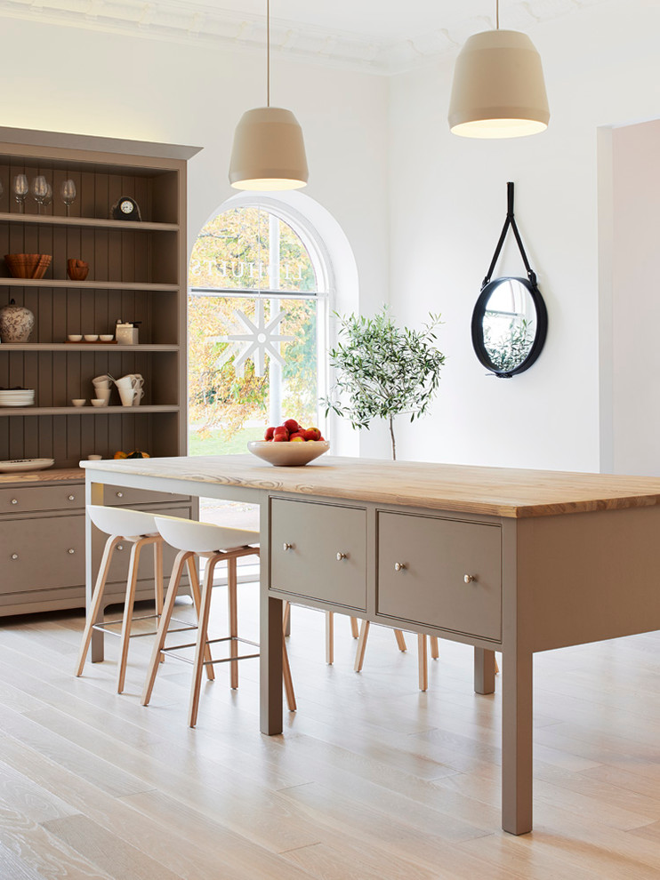 Photo of a mid-sized scandinavian eat-in kitchen in Other with beaded inset cabinets, light hardwood floors, with island and wood benchtops.