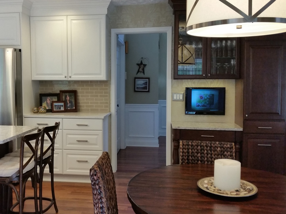 Mid-sized transitional l-shaped medium tone wood floor and brown floor eat-in kitchen photo with raised-panel cabinets, white cabinets, quartz countertops, subway tile backsplash, stainless steel appliances, an island, beige backsplash and white countertops