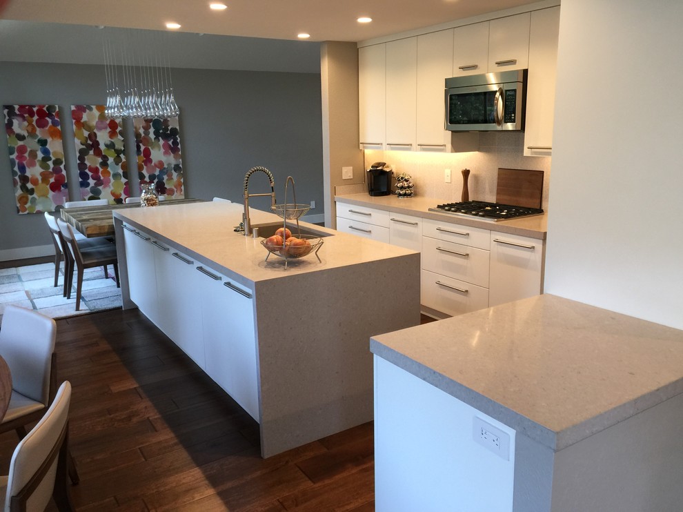 Inspiration for a mid-sized contemporary u-shaped kitchen pantry in San Francisco with an undermount sink, flat-panel cabinets, white cabinets, granite benchtops, grey splashback, stone slab splashback, stainless steel appliances, medium hardwood floors and multiple islands.