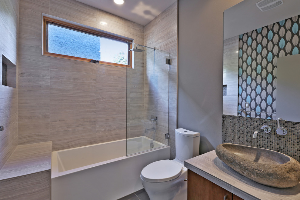 Design ideas for a mid-sized contemporary bathroom in Portland with a vessel sink, flat-panel cabinets, medium wood cabinets, tile benchtops, an alcove tub, a shower/bathtub combo, a one-piece toilet, gray tile, porcelain tile, grey walls and porcelain floors.