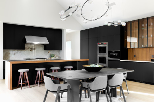 Minimalist kitchen with matte black flat-panel kitchen cabinet walls, warm wood accents and glass display uppers, a long island with seating, marble backsplash, and built-in stainless appliances.