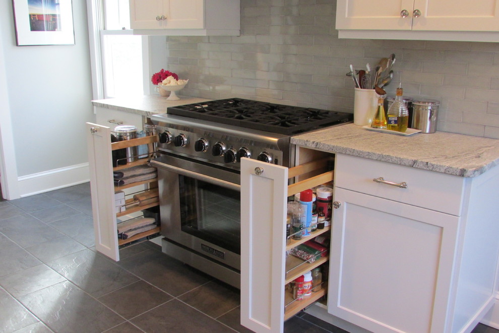 Example of a transitional slate floor eat-in kitchen design in New York with a farmhouse sink, recessed-panel cabinets, white cabinets and paneled appliances