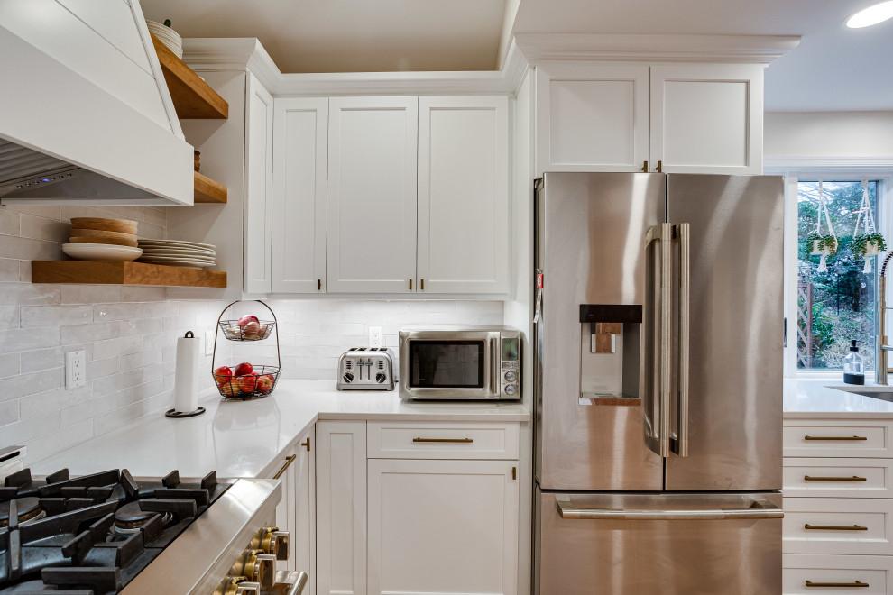 This is an example of a large modern u-shaped eat-in kitchen in DC Metro with recessed-panel cabinets, white cabinets, quartz benchtops, white splashback, subway tile splashback, stainless steel appliances and a peninsula.