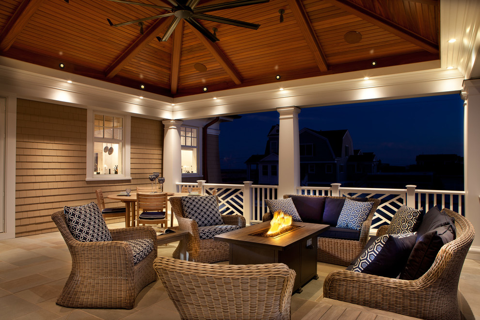 Photo of a large beach style backyard patio in New York with a fire feature, tile and a roof extension.
