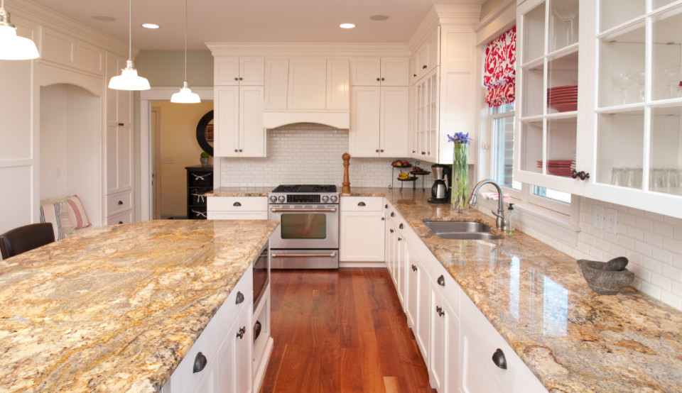 Inspiration for a mid-sized transitional l-shaped medium tone wood floor enclosed kitchen remodel in Toronto with an undermount sink, recessed-panel cabinets, white cabinets, granite countertops, white backsplash, ceramic backsplash, stainless steel appliances and an island
