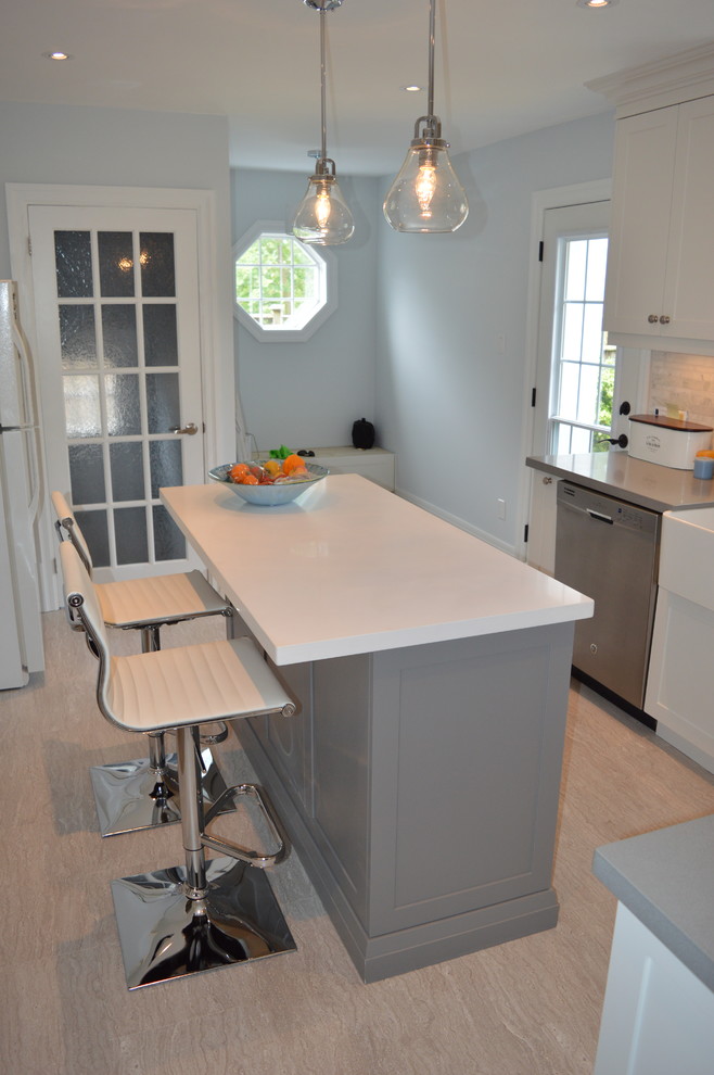 Example of a mid-sized transitional l-shaped vinyl floor and beige floor eat-in kitchen design in Toronto with a farmhouse sink, shaker cabinets, white cabinets, quartz countertops, gray backsplash, stainless steel appliances, an island and stone tile backsplash