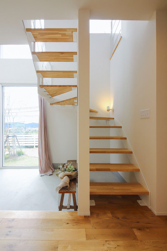 Modern wood floating metal railing staircase in Other with wallpapered walls and feature lighting.