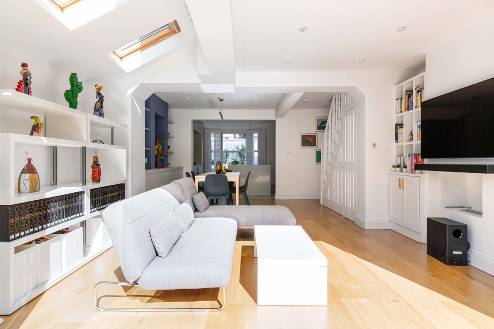 Großes, Offenes Modernes Wohnzimmer mit weißer Wandfarbe, braunem Holzboden und TV-Wand in London