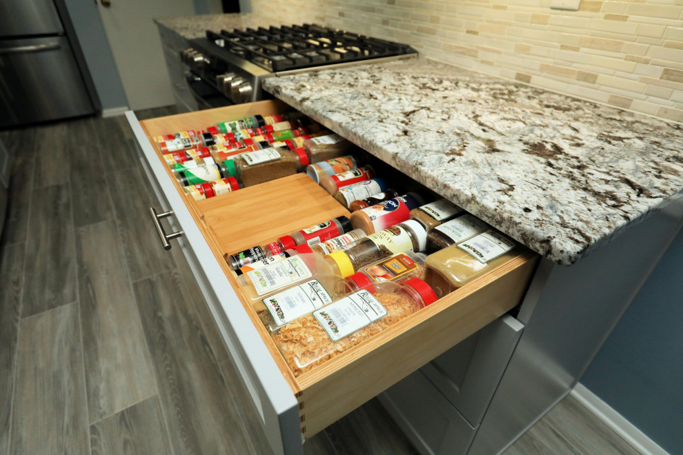 Transitional vinyl floor and gray floor kitchen photo with a double-bowl sink, shaker cabinets, gray cabinets, granite countertops, mosaic tile backsplash, stainless steel appliances, an island and multicolored countertops