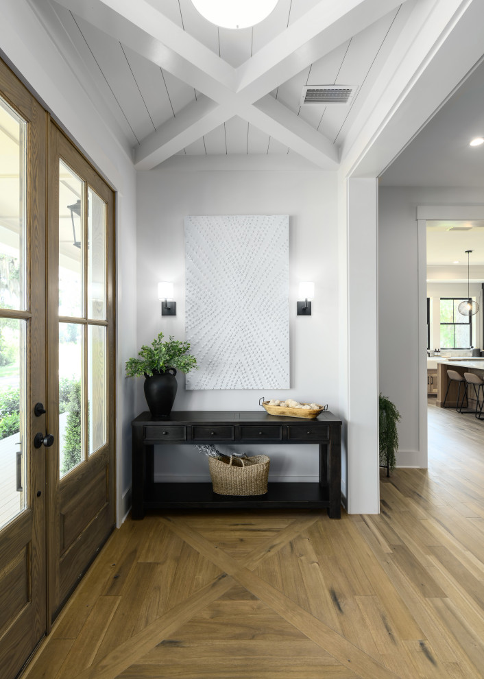 Inspiration for a small country front door in Jacksonville with white walls, light hardwood floors, a single front door, a medium wood front door, brown floor and exposed beam.