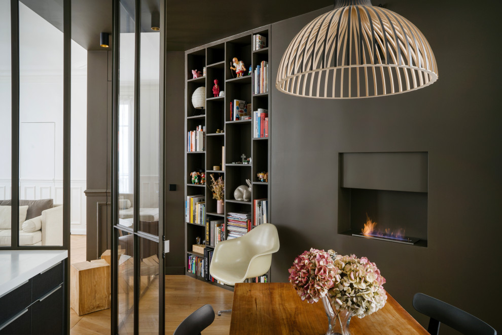 Inspiration for a contemporary dining room in Paris with black walls, medium hardwood floors, a ribbon fireplace and brown floor.