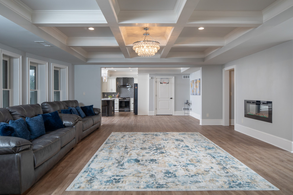 Large transitional walk-out basement in Atlanta with blue walls, laminate floors, a hanging fireplace, a brick fireplace surround and brown floor.