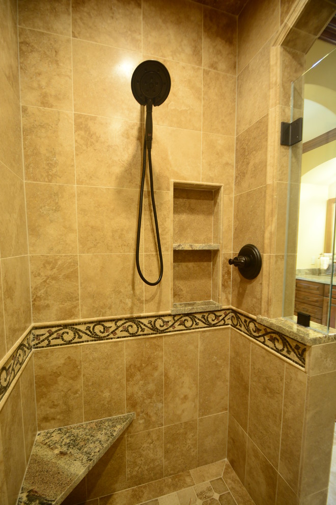 This is an example of an expansive mediterranean master bathroom in Milwaukee with raised-panel cabinets, medium wood cabinets, a freestanding tub, a double shower, a two-piece toilet, beige tile, beige walls, limestone floors, a vessel sink, granite benchtops, beige floor, a hinged shower door, stone tile and a shower seat.