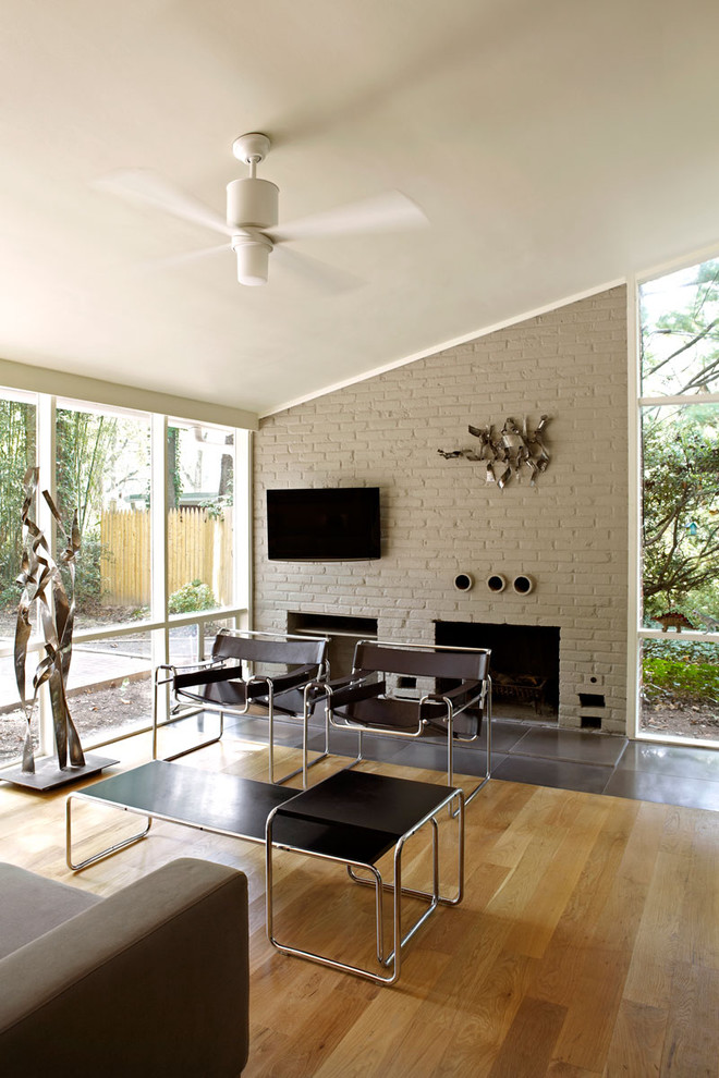 This is an example of a midcentury living room in DC Metro with a standard fireplace and a brick fireplace surround.