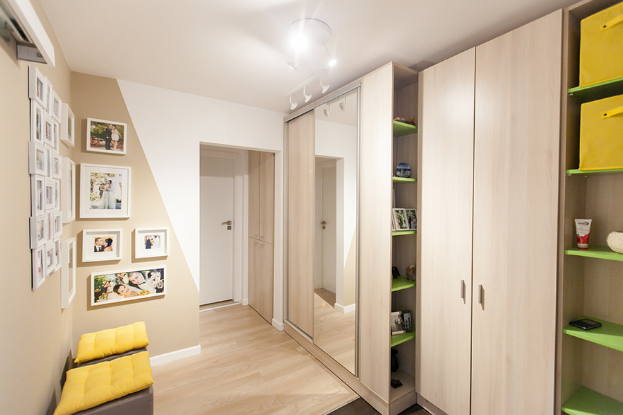 Photo of a small contemporary hallway in Other with beige walls and light hardwood floors.