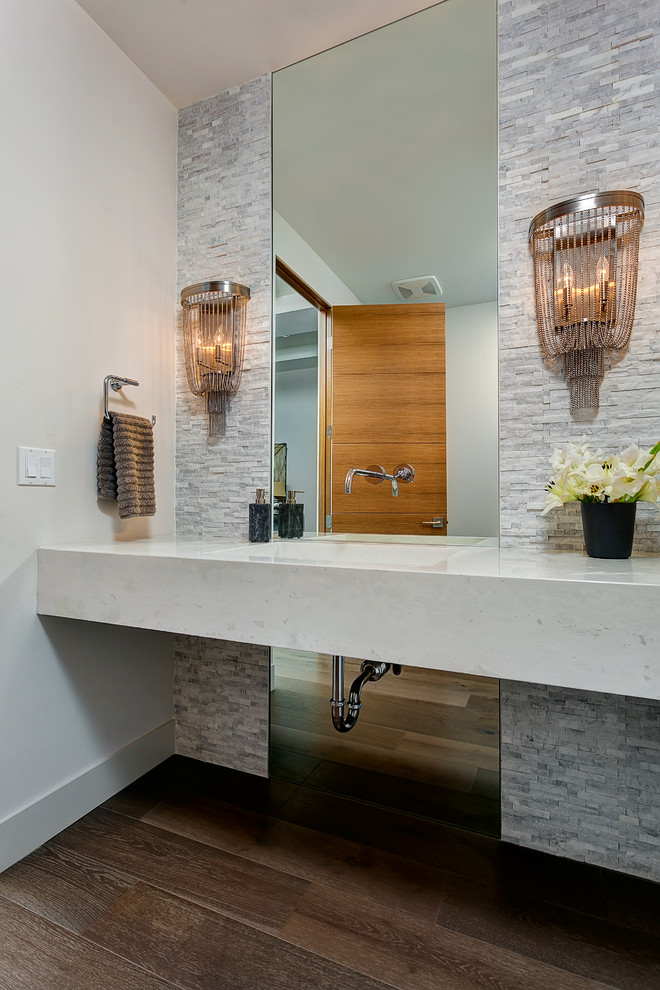Contemporary powder room in Boise with an integrated sink, gray tile, stone tile, dark hardwood floors, white walls and white benchtops.