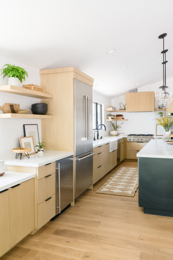 Photo of a mid-sized scandinavian l-shaped eat-in kitchen in Orange County with a farmhouse sink, flat-panel cabinets, brown cabinets, quartz benchtops, white splashback, ceramic splashback, stainless steel appliances, light hardwood floors, with island, brown floor, white benchtop and vaulted.