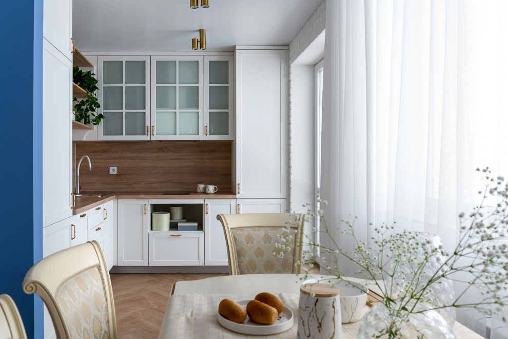 Inspiration for a medium sized classic l-shaped kitchen/diner in Other with a submerged sink, raised-panel cabinets, white cabinets, laminate countertops, brown splashback, wood splashback, stainless steel appliances, medium hardwood flooring, no island, beige floors and brown worktops.