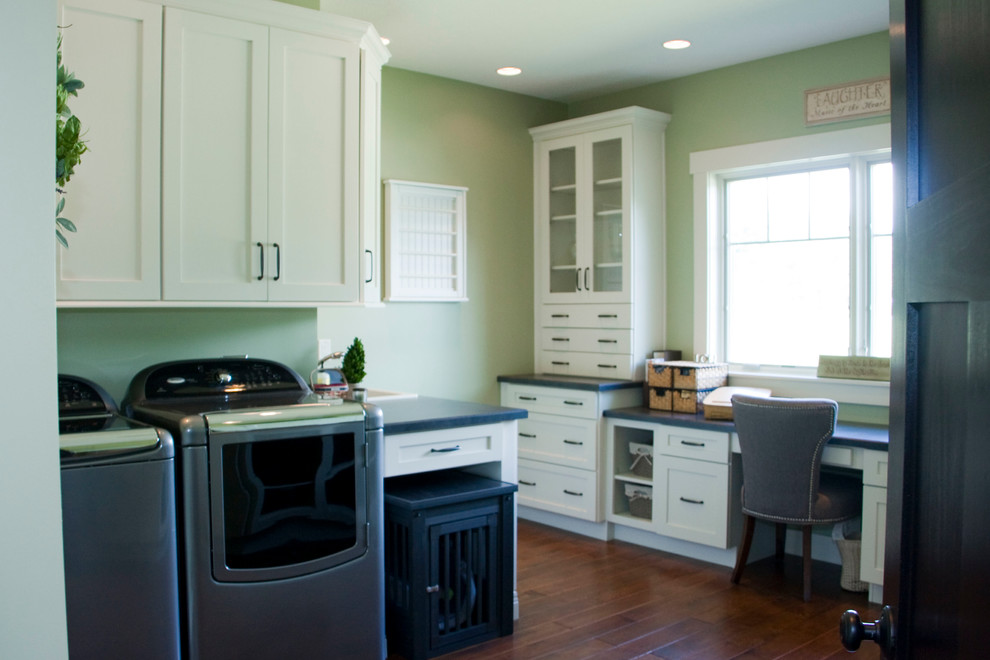 Design ideas for a mid-sized traditional utility room in Other with a drop-in sink, shaker cabinets, white cabinets, laminate benchtops, green walls, medium hardwood floors and a side-by-side washer and dryer.