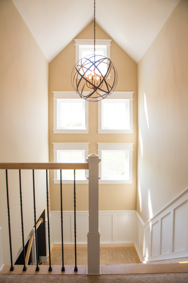 This is an example of an expansive arts and crafts painted wood l-shaped staircase in Burlington with wood risers.