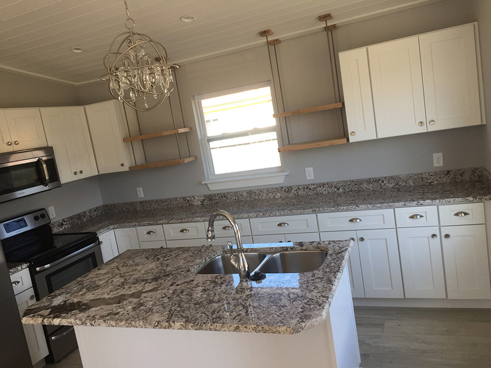 Inspiration for a mid-sized country l-shaped open plan kitchen in Miami with a double-bowl sink, shaker cabinets, white cabinets, granite benchtops, stainless steel appliances, medium hardwood floors, with island, brown floor and brown benchtop.