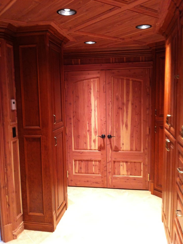 This is an example of a mid-sized traditional men's walk-in wardrobe in Tampa with raised-panel cabinets, light wood cabinets and light hardwood floors.