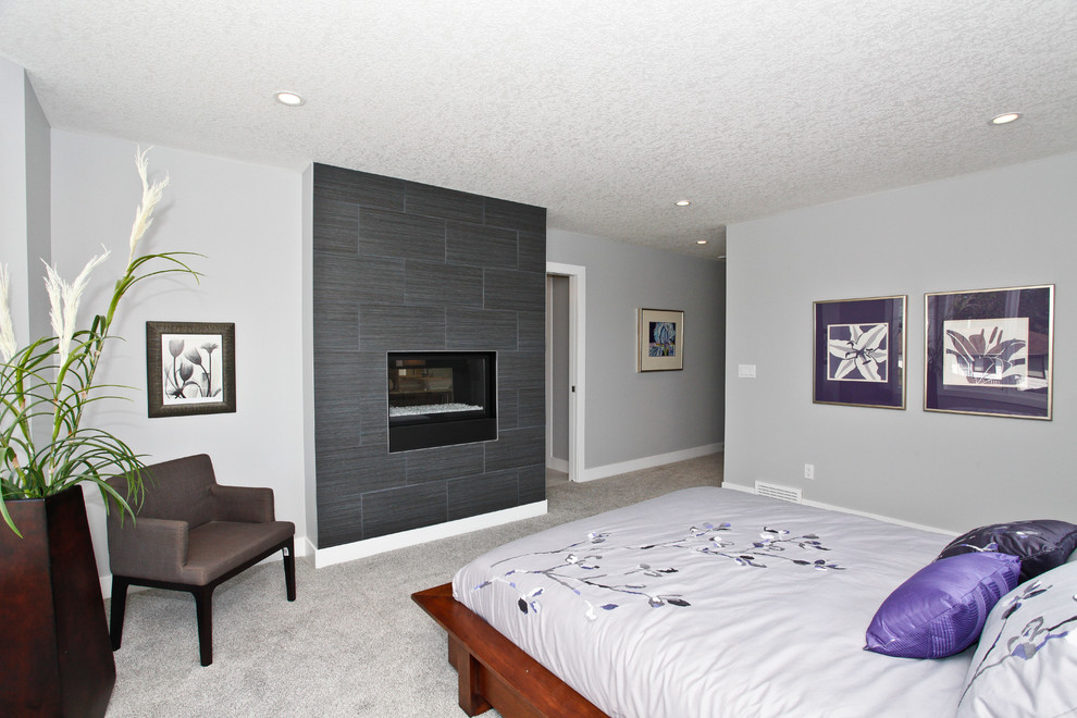 Photo of a mid-sized contemporary master bedroom in Calgary with grey walls, carpet, a standard fireplace and a tile fireplace surround.