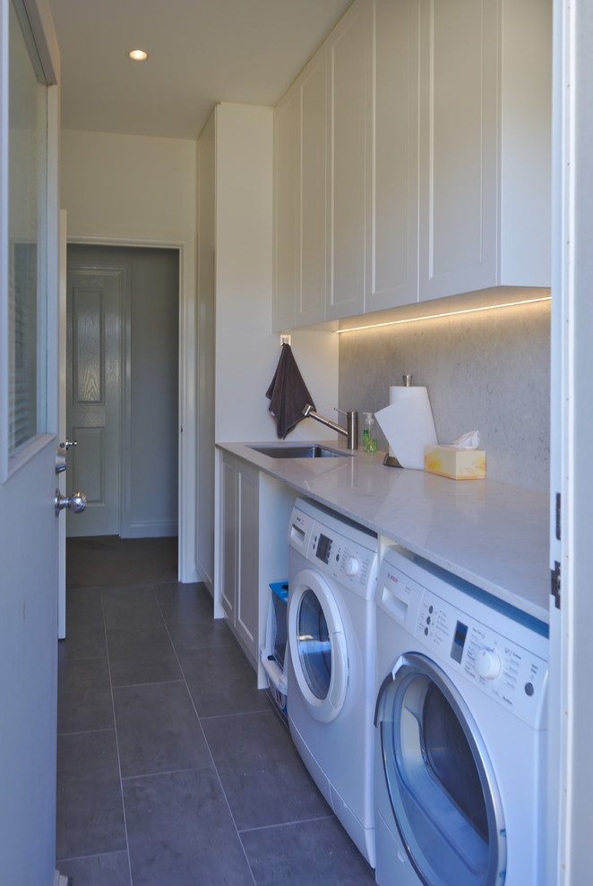 Design ideas for a mid-sized transitional galley laundry room in Melbourne with an undermount sink, recessed-panel cabinets, white cabinets, quartz benchtops, white walls, medium hardwood floors, a side-by-side washer and dryer, brown floor and beige benchtop.