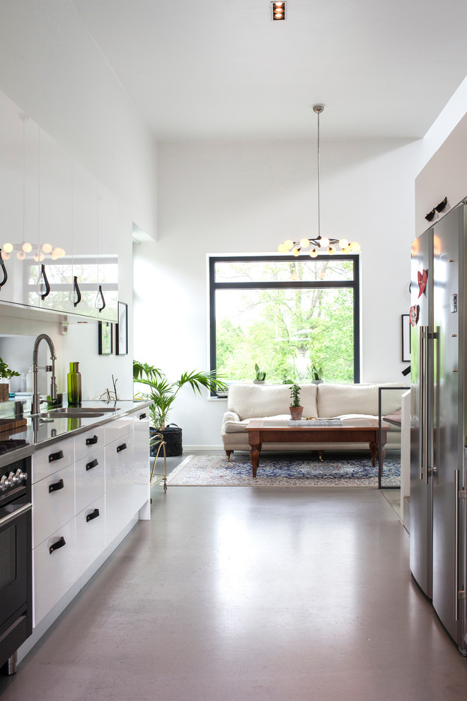 Photo of a mid-sized contemporary single-wall kitchen in Stockholm with flat-panel cabinets, white cabinets, stainless steel appliances, a double-bowl sink, stainless steel benchtops, concrete floors and no island.