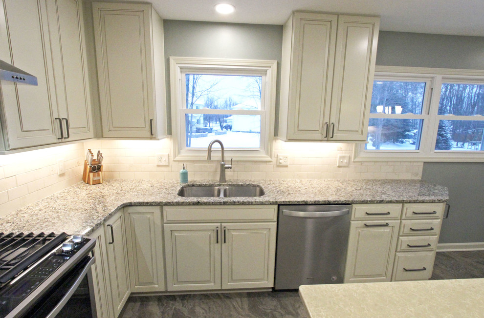 Mid-sized transitional galley eat-in kitchen in Cleveland with an undermount sink, raised-panel cabinets, white cabinets, granite benchtops, beige splashback, glass sheet splashback, stainless steel appliances, vinyl floors, with island, grey floor and beige benchtop.