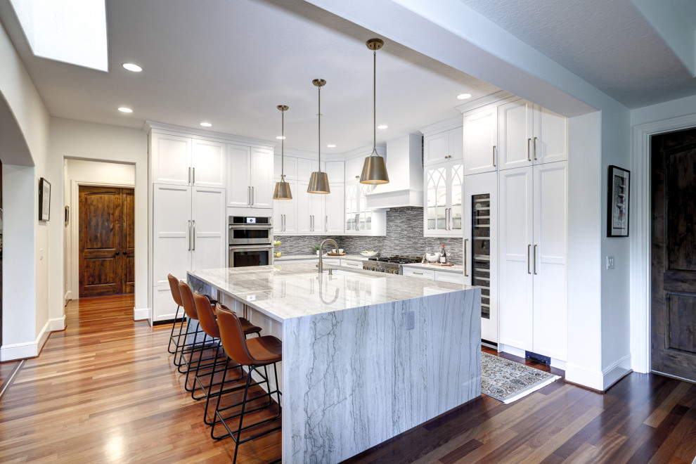 This is an example of a large transitional l-shaped eat-in kitchen in Portland with an undermount sink, shaker cabinets, white cabinets, quartzite benchtops, grey splashback, glass sheet splashback, panelled appliances, medium hardwood floors, with island, red floor and white benchtop.
