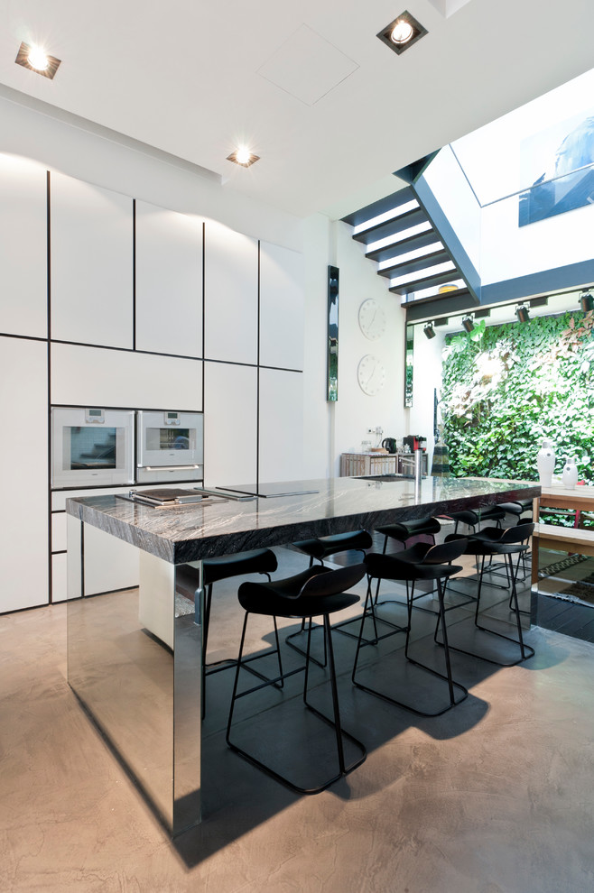 This is an example of a contemporary open plan kitchen in Singapore with white cabinets, flat-panel cabinets and white appliances.
