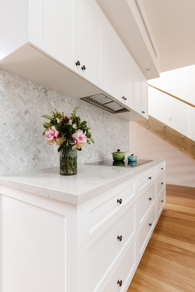Example of a mid-sized transitional u-shaped light wood floor and brown floor eat-in kitchen design in DC Metro with an undermount sink, recessed-panel cabinets, white cabinets, quartz countertops, white backsplash, marble backsplash, stainless steel appliances, a peninsula and white countertops
