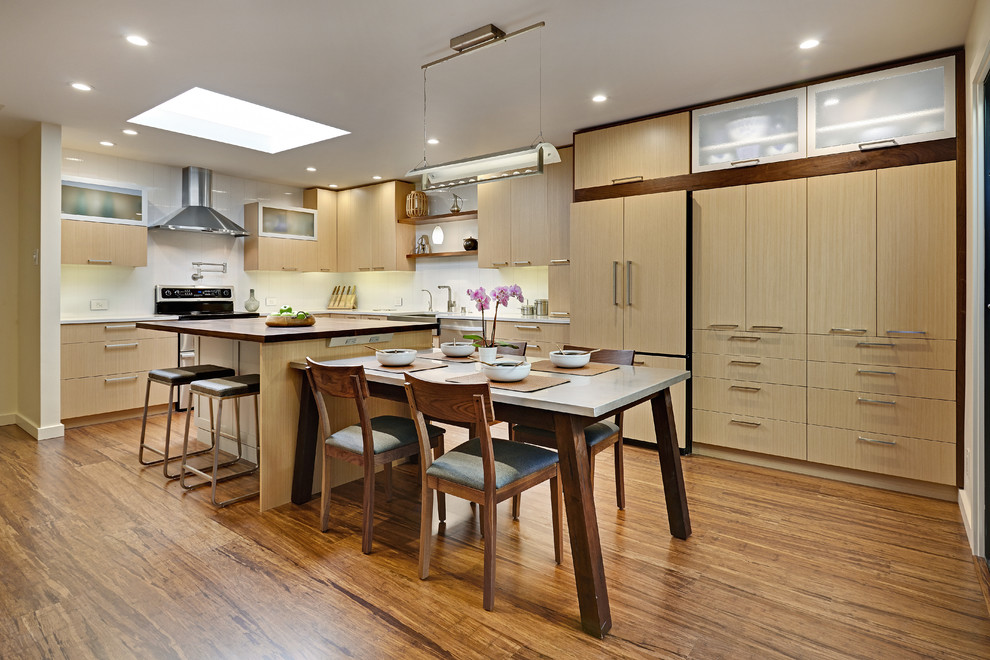 Photo of a contemporary l-shaped eat-in kitchen in Other with a farmhouse sink, flat-panel cabinets, light wood cabinets, white splashback, panelled appliances, quartz benchtops and porcelain splashback.