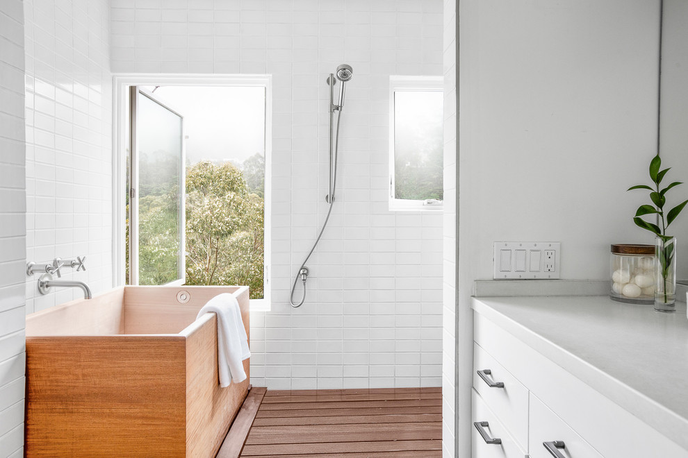 Contemporary bathroom in San Francisco with flat-panel cabinets, white cabinets, a freestanding tub, a curbless shower, white tile, subway tile, white walls, medium hardwood floors, brown floor, an open shower and grey benchtops.