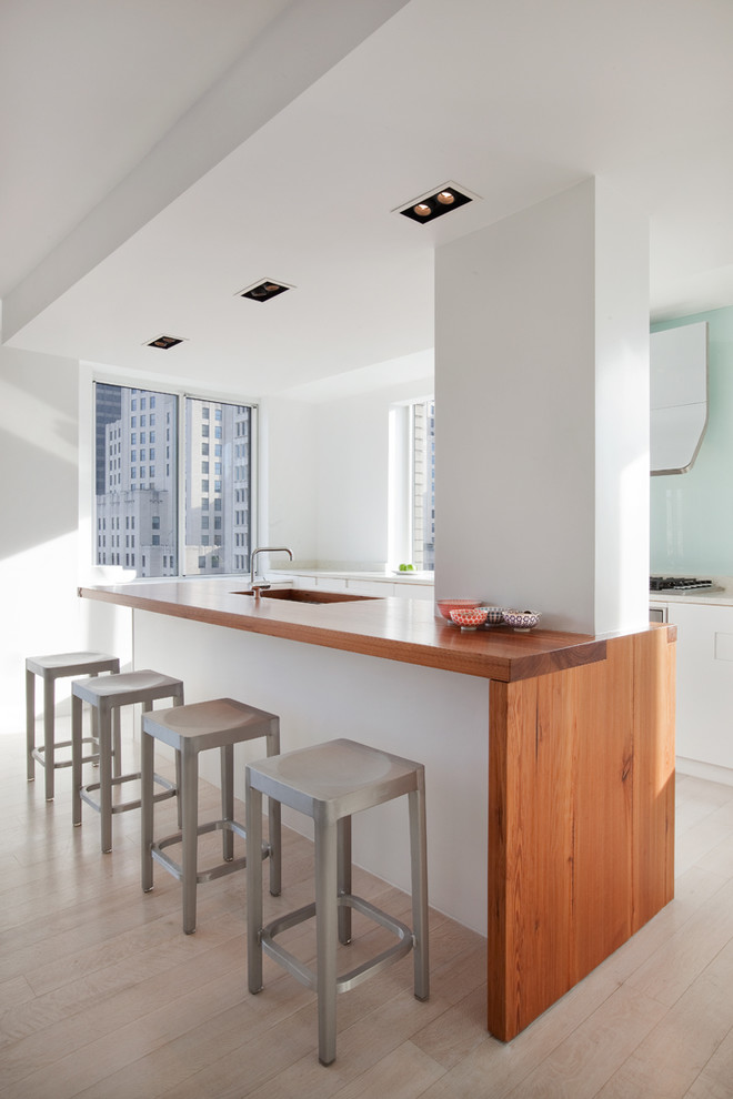 This is an example of a modern kitchen in New York with wood benchtops.