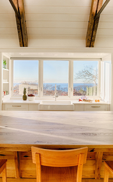 Inspiration for a transitional l-shaped open concept kitchen remodel with a farmhouse sink, shaker cabinets, white cabinets, wood countertops, white backsplash, stone slab backsplash, paneled appliances and an island