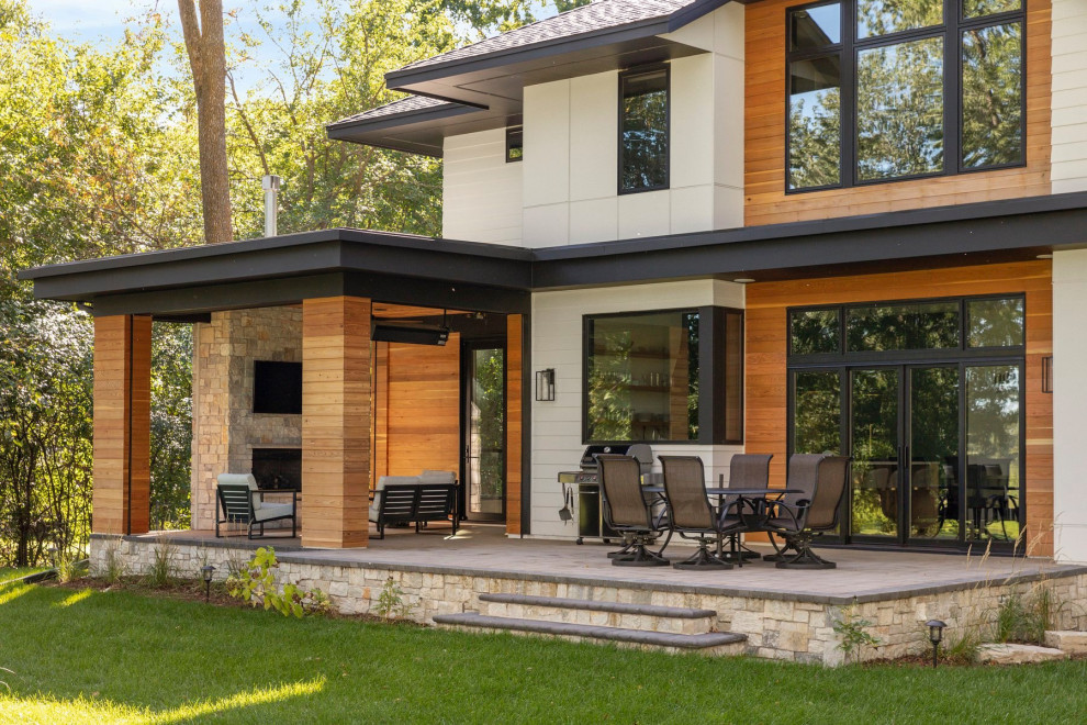 Inspiration for a contemporary backyard stone patio remodel in Minneapolis with a roof extension