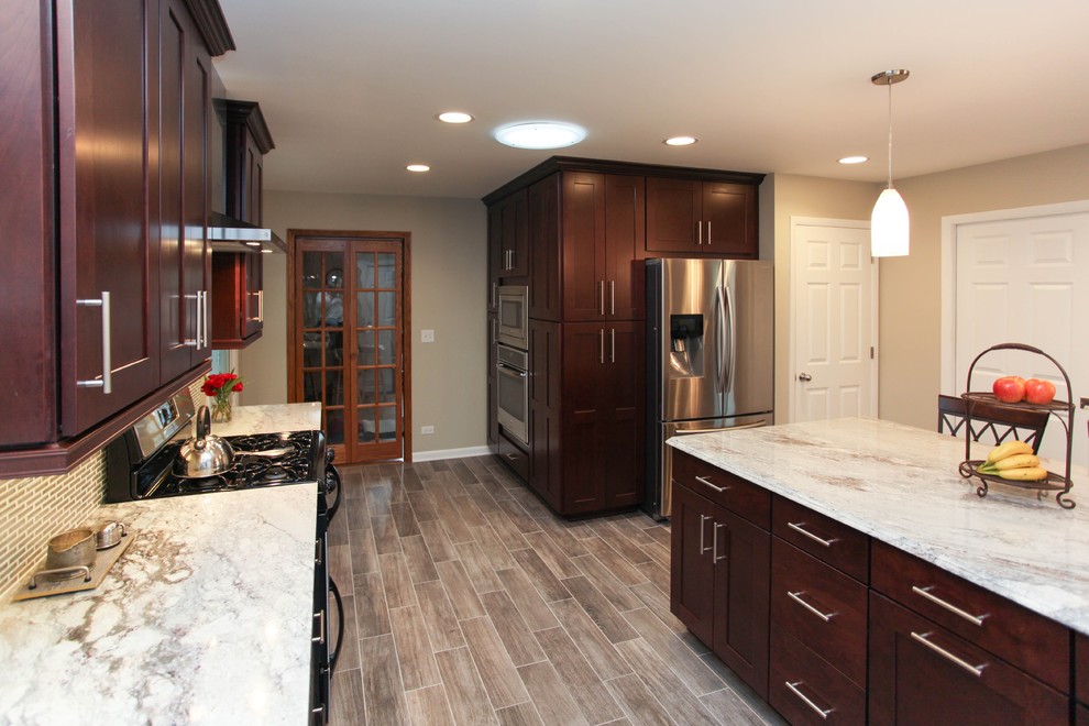 Eat-in kitchen - large transitional u-shaped porcelain tile eat-in kitchen idea in Chicago with an undermount sink, recessed-panel cabinets, dark wood cabinets, granite countertops, gray backsplash, glass tile backsplash, stainless steel appliances and an island