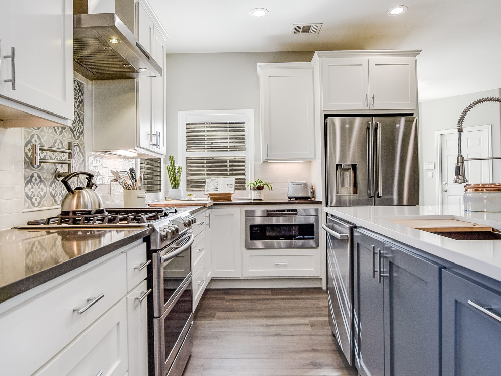 This is an example of a mid-sized country l-shaped eat-in kitchen in Austin with an undermount sink, flat-panel cabinets, grey cabinets, quartz benchtops, blue splashback, cement tile splashback, stainless steel appliances, porcelain floors, with island, grey floor, white benchtop and vaulted.