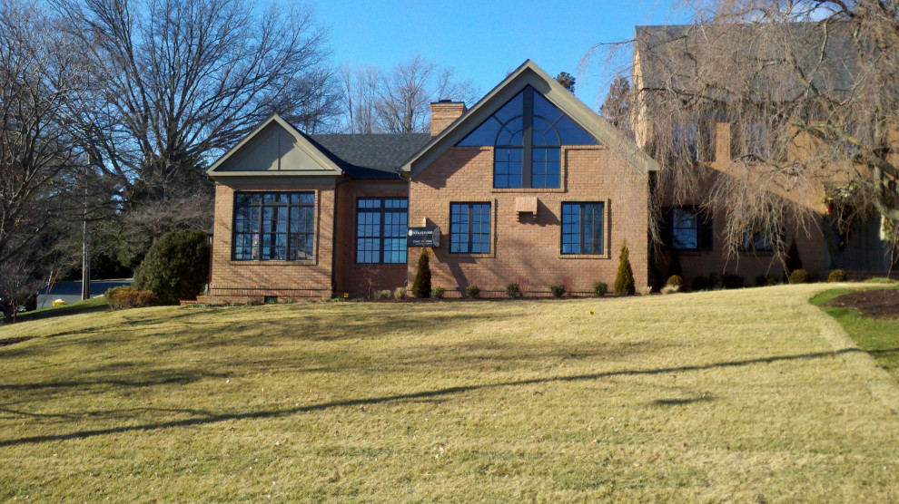 Large brown three-story brick house exterior photo with a shingle roof