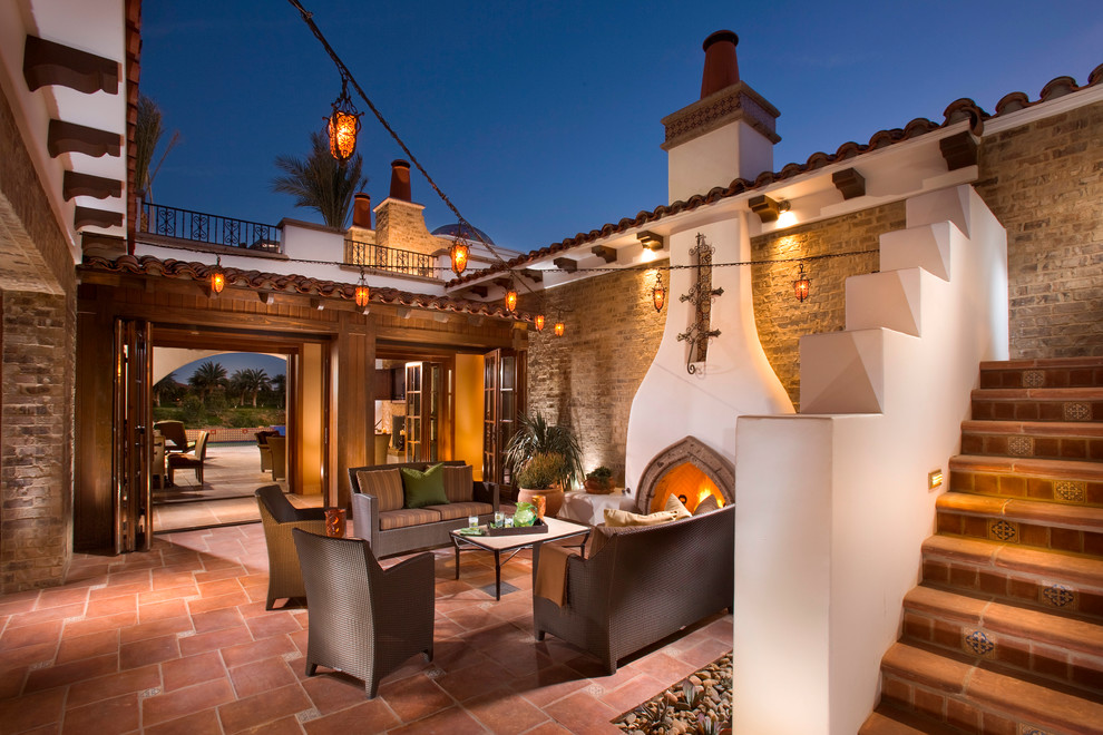 This is an example of a mediterranean courtyard patio in Orange County with tile, no cover and with fireplace.