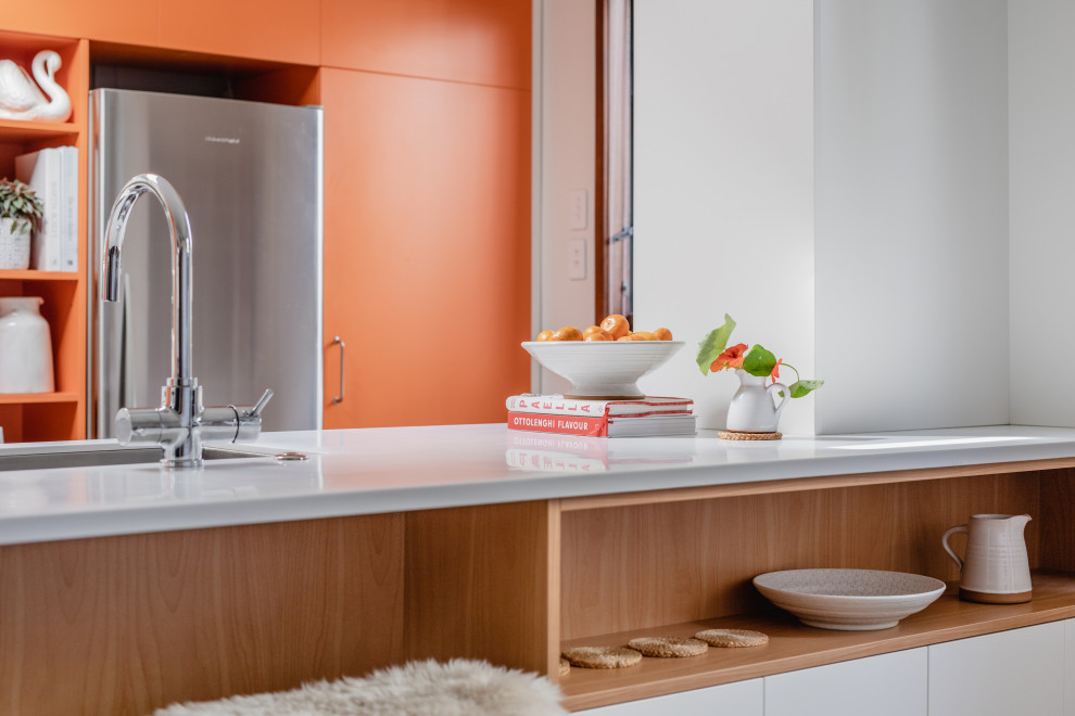 Esempio di una cucina minimalista di medie dimensioni con lavello a vasca singola, ante lisce, ante arancioni, top in superficie solida, elettrodomestici in acciaio inossidabile, pavimento in cemento, penisola, pavimento grigio, top bianco e soffitto in legno