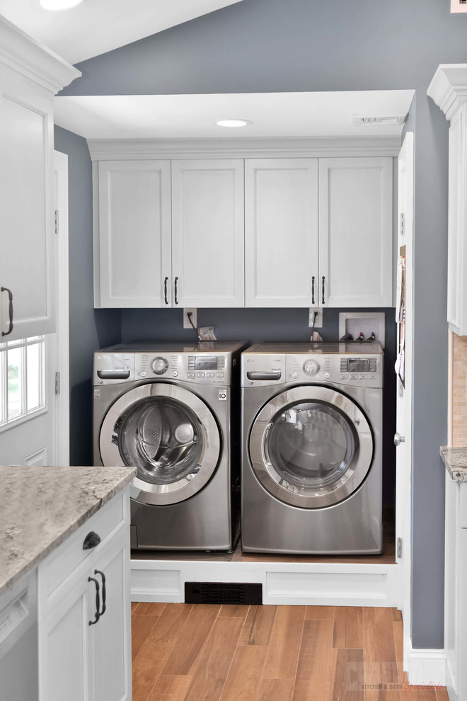Photo of a large galley laundry room in New York with an undermount sink, raised-panel cabinets, white cabinets, quartz benchtops, beige splashback and grey benchtop.